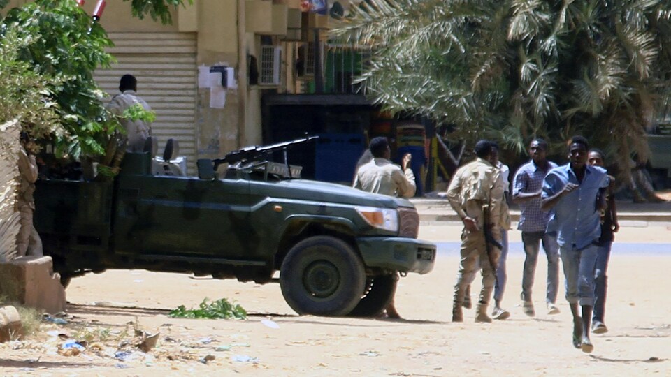 People run near a truck with a machine gun. 