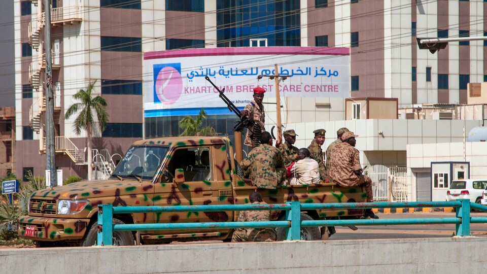 Des soldats assis sur une camionnette munie d'une mitraillette.
