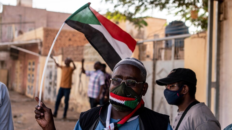 Un manifestant dans la rue tient un drapeau du Soudan.