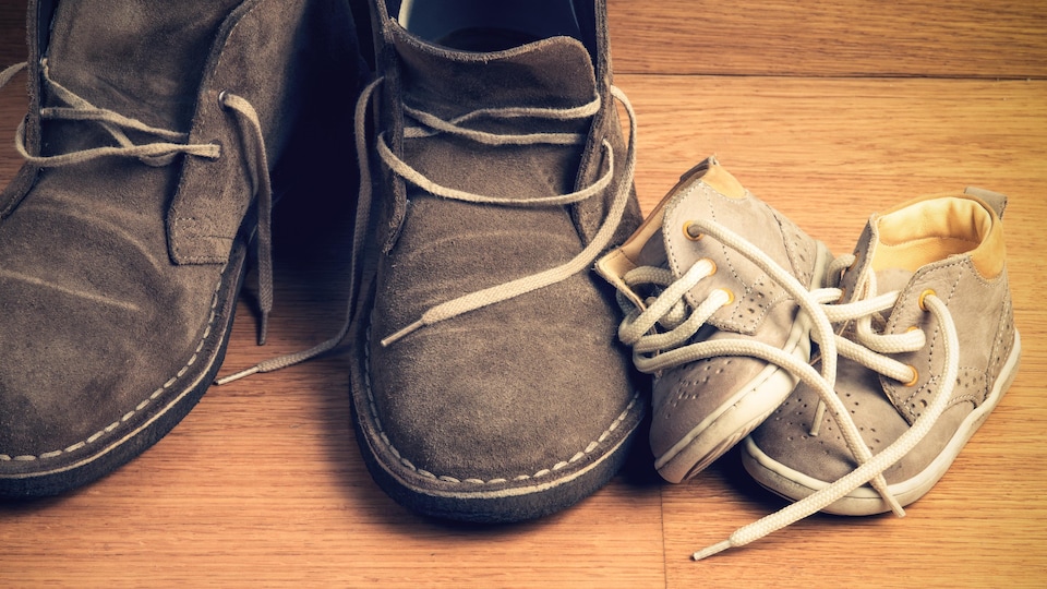 Les chaussures d'un enfant posées à côté de celles d'un adulte.