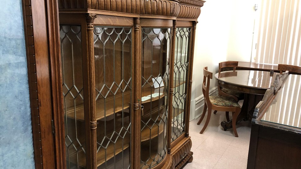 Une grosse armoire en bois vitrée et une table de cuisine sont en montre. 
