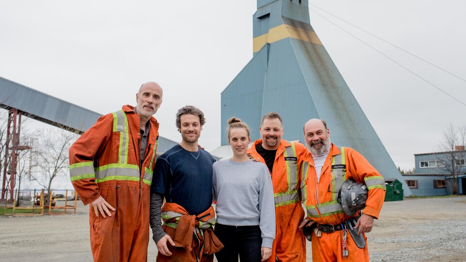 Des acteurs, dont James Hyndman et Michaël Gouin, posent en compagnie de Sophie Dupuis sur un site minier, habillés en mineurs.
