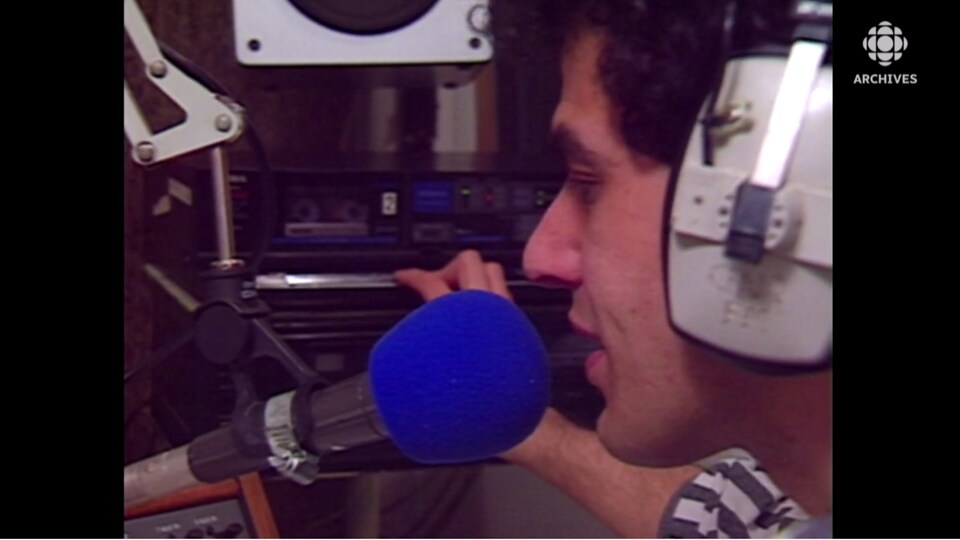 Homme qui parle dans un micro de radio devant une console d'enregistrement.