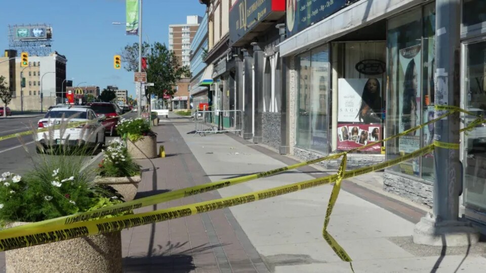 Une section de trottoir est délimitée avec du ruban de police jaune.