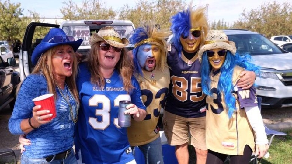 Des supporters des Blue Bombers au Banjo Bowl vêtus des couleurs de leur équipe au stade Investors Group Field de Winnipeg.