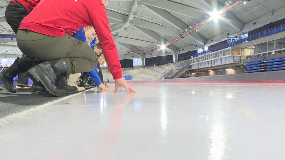 De jeunes athlètes français se penchent pour toucher la patinoire de l'Anneau olympique de Calgary.
