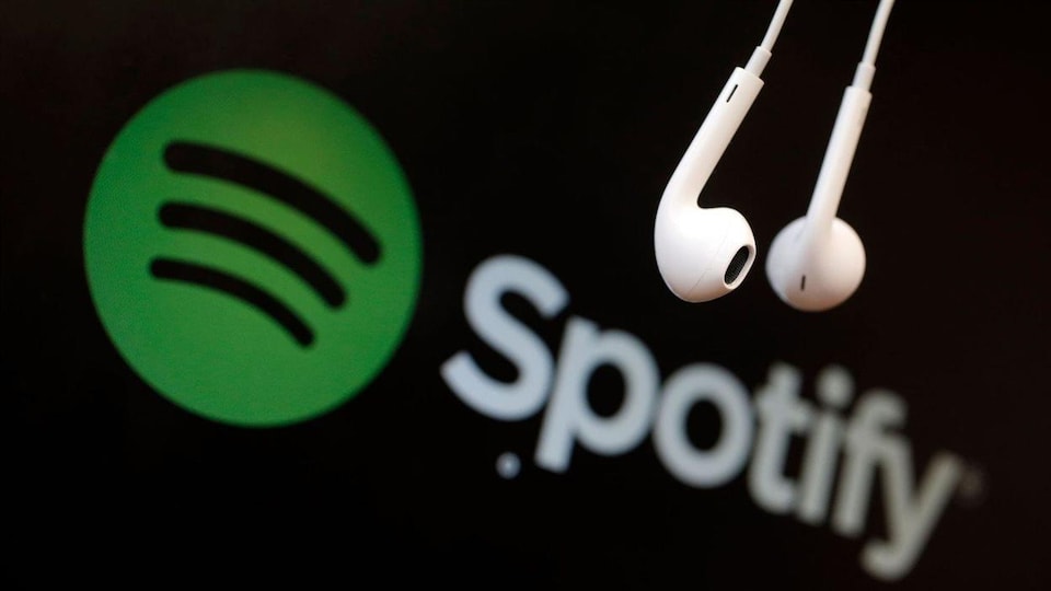 Le logo de Spotify sur fond noir avec de petits écouteurs avec fil qui pendent devant.