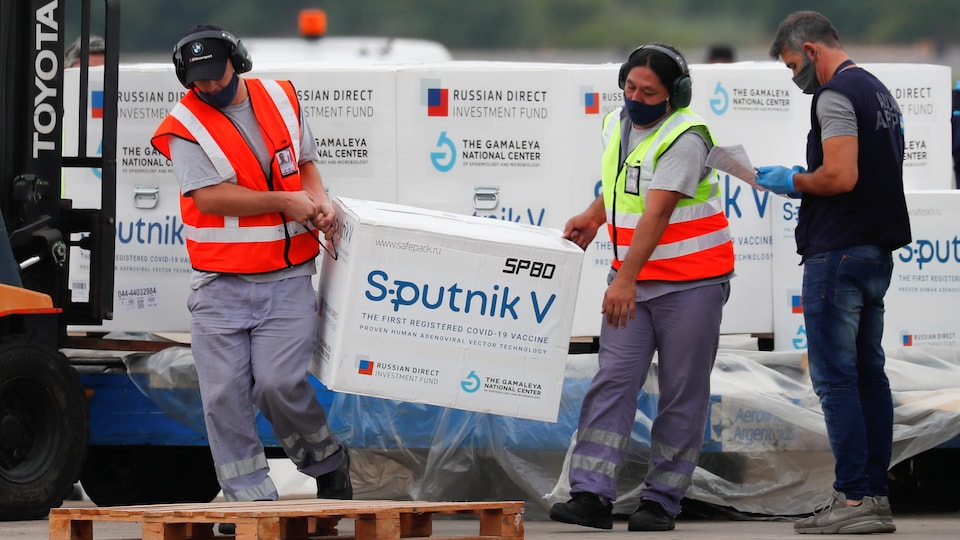 Deux personnes transportent une boîte du vaccin Spoutnik.