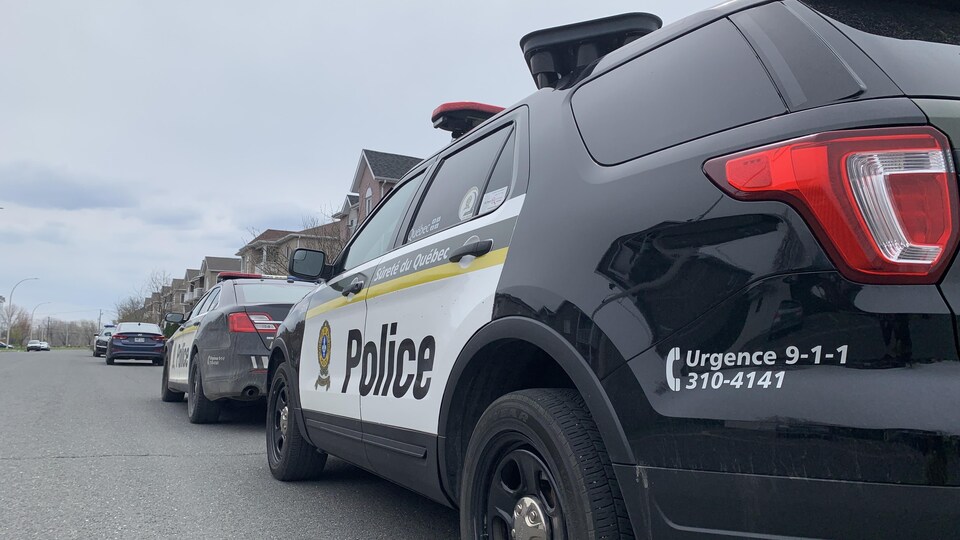 Deux voitures de patrouille stationnée une derrière l'autre dans une rue.