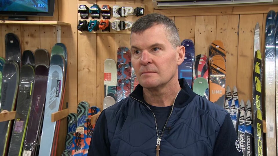 Brad Squires interviewé devant un étalage de skis.