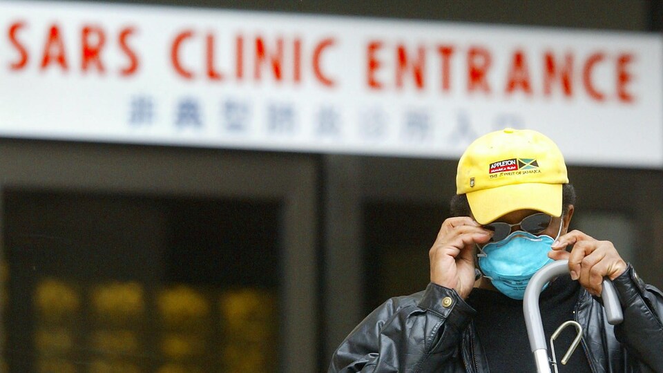 Un homme ajuste son masque à l'extérieur d'une clinique du SRAS en 2003.