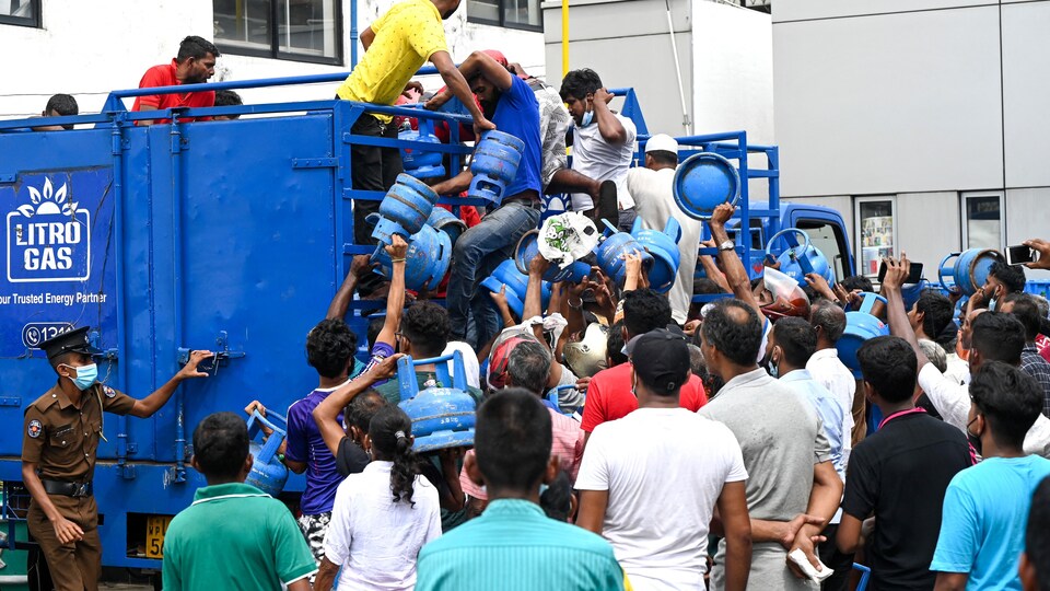 Citizens rush towards the Litro Gas truck, in front of a helpless policeman.