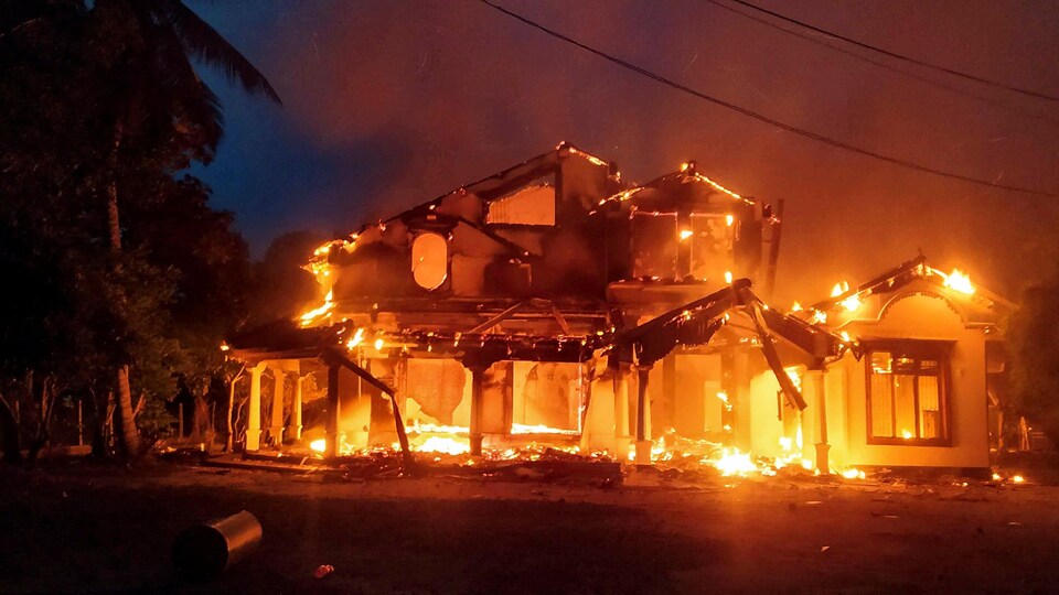 Une maison en proie aux flammes en pleine nuit. 