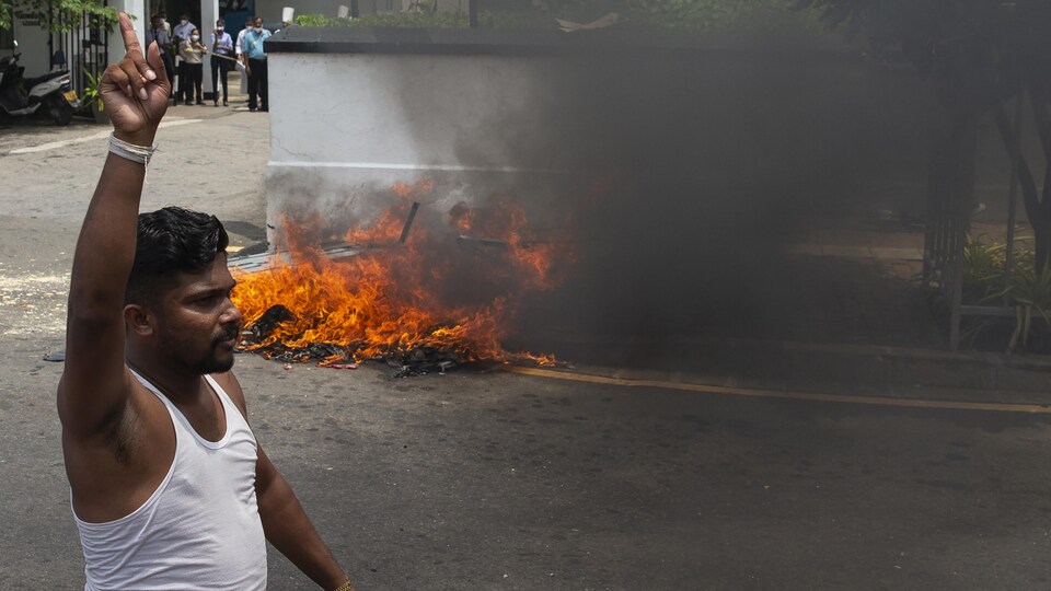 Un manifestant pro-gouvernement devant un feu allumé dans une rue au Sri Lanka.