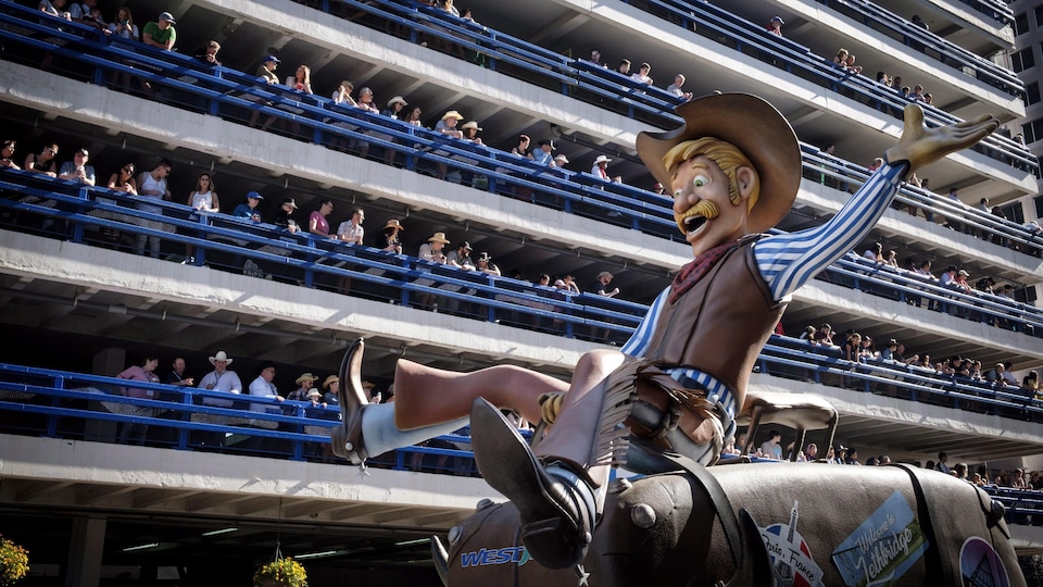 Les spectateurs regardent une représentation de cowboy qui fait du rodéo passer.