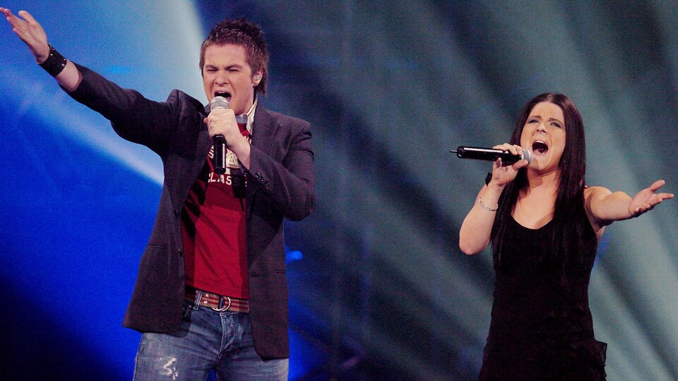 Les deux interprètes chantent dans un micro.
