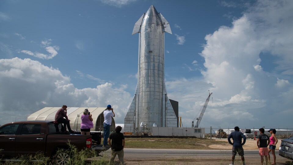 Des gens regardent un prototype du vaisseau d'acier inoxydable de SpaceX.