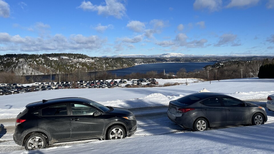 Des voitures sont stationnées devant une rivière l'hiver.