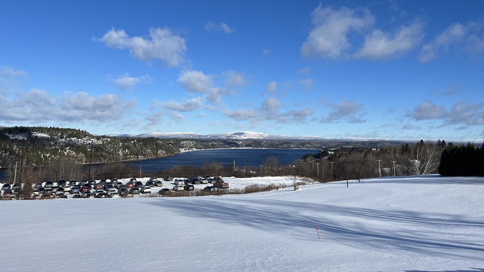 Un stationnement, une rivière et des montagnes en hiver.