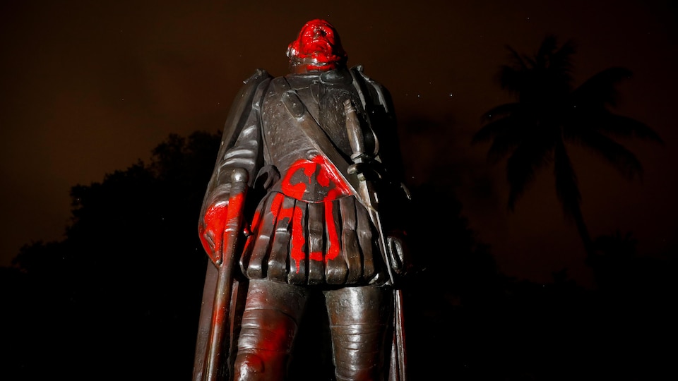 Une statue vandalisée avec de la peinture rouge.
