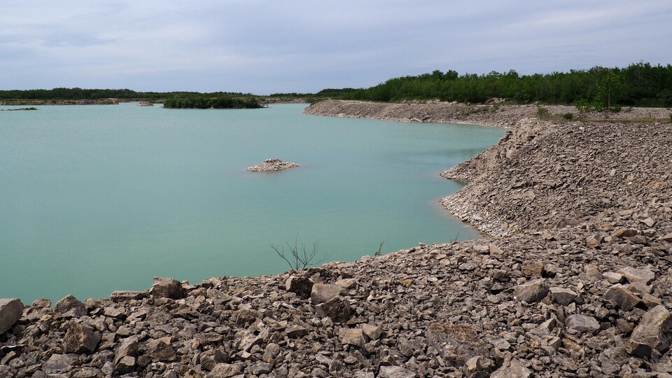 Un plan d'eau turquoise dans un paysage rocailleux.