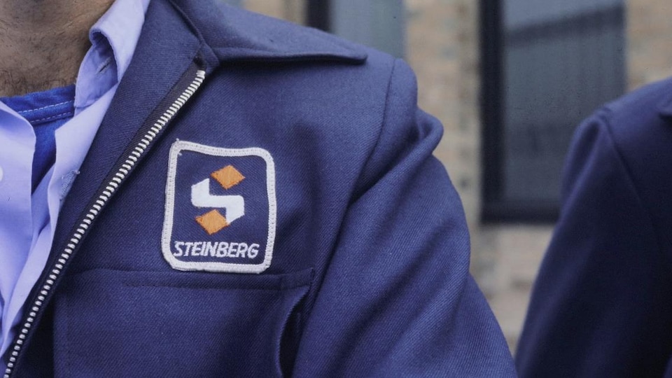 Logo de Steinberg sur le blouson d'un employé.