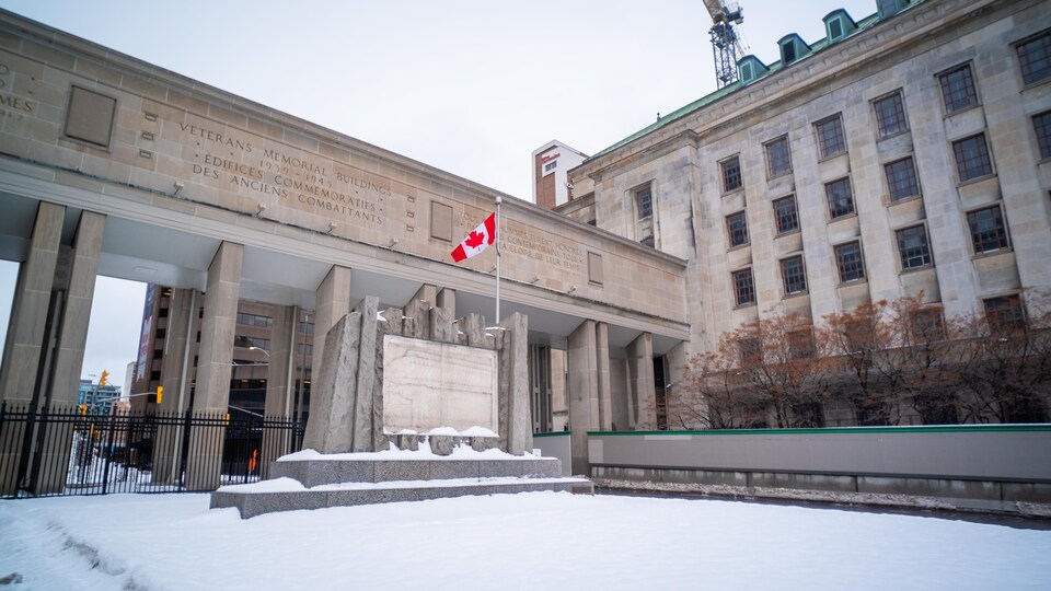 Un terre-plein enneigé avec une plaque commémorative entre deux édifices d'Ottawa. 