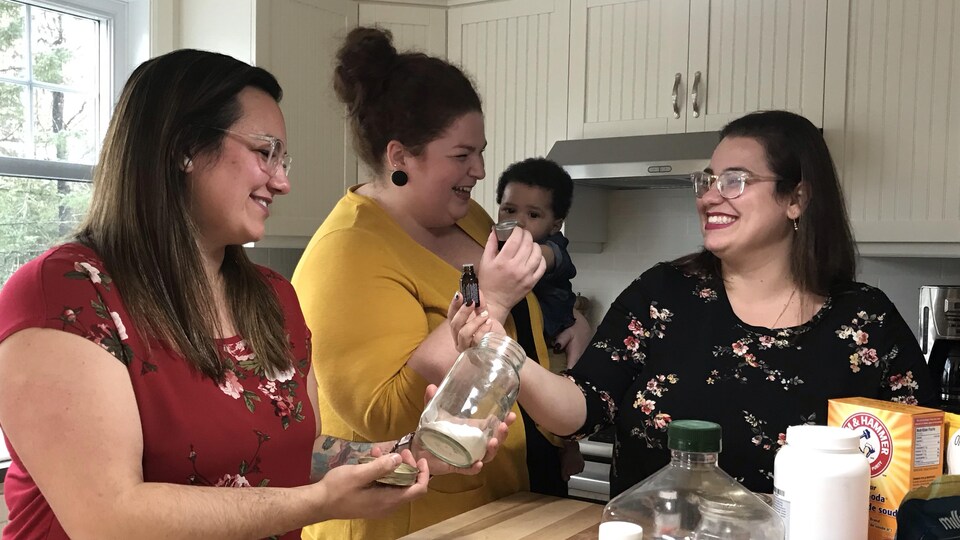 Trois femmes et un bébé devant un comptoir de cuisine.