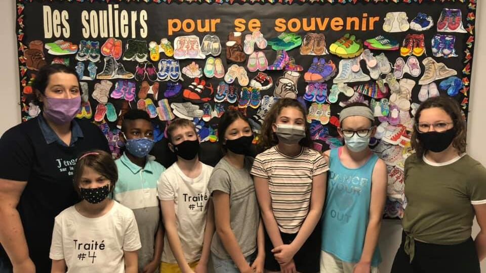 Des élèves se trouvent devant un babillard où l'on retrouve des souliers colorés.