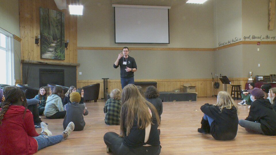 Steve Jodoin parle devant un groupe de jeunes assis.