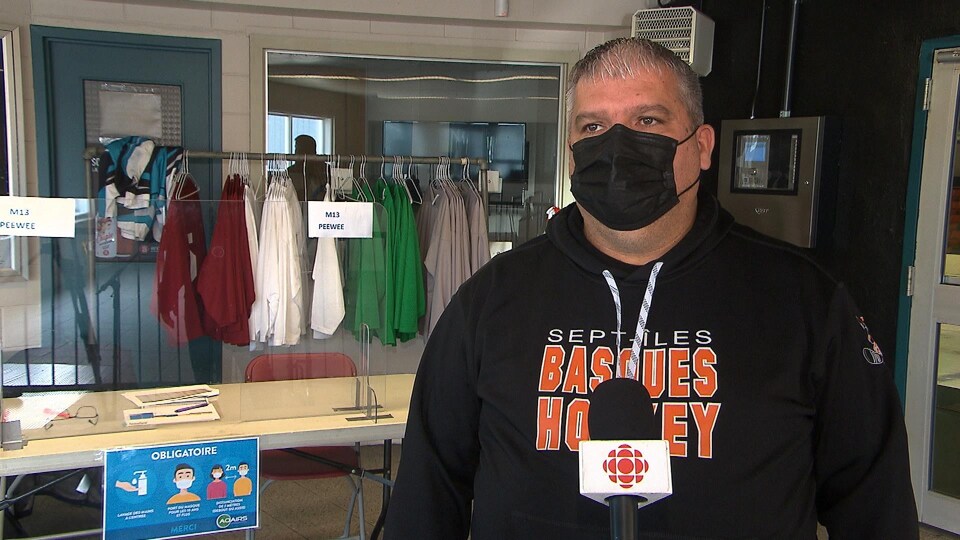 Le président de l'association du hockey mineur de Sept-Îles, Steve Lebel, portant un masque et répondant aux questions de Radio-Canada.