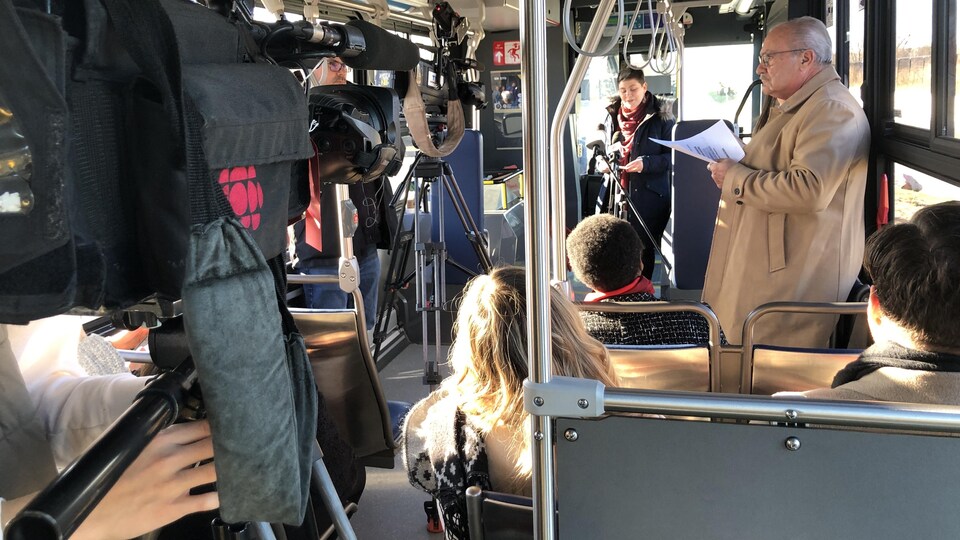 Des personnes à l'intérieur d'un autobus s'adressent aux journalistes.