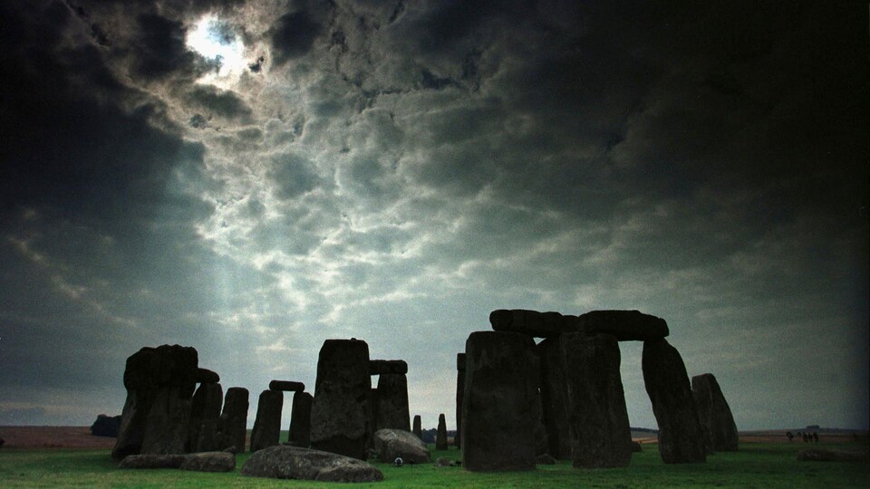 On voit le monument de pierres dressées de Stonehenge, sous un ciel nuageux.