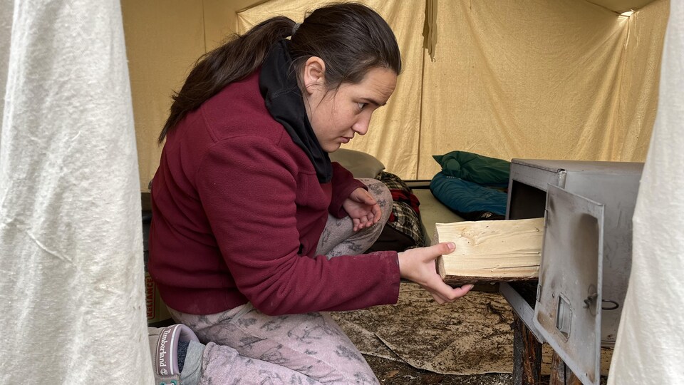 Sue Vollant place une bûche dans le poêle à bois de sa tente prospecteur.
