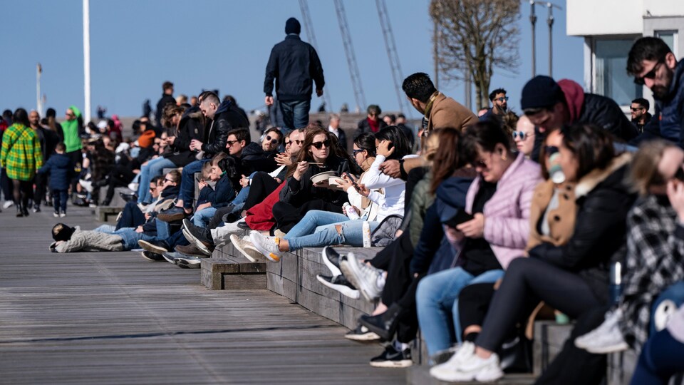 Des dizaines de personnes flânent sur un quai.