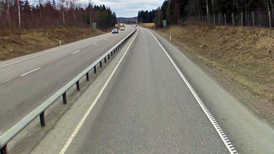 Une route à deux directions en Suède l'été, séparée par une barrière. 
