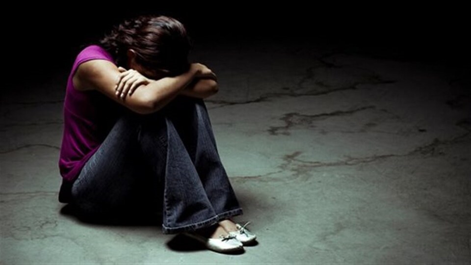 Une jeune fille assise, les bras croisés.