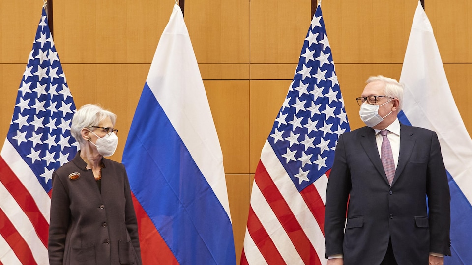 Deux diplomates devant les drapeaux de leurs pays, les États-Unis et la Russie.