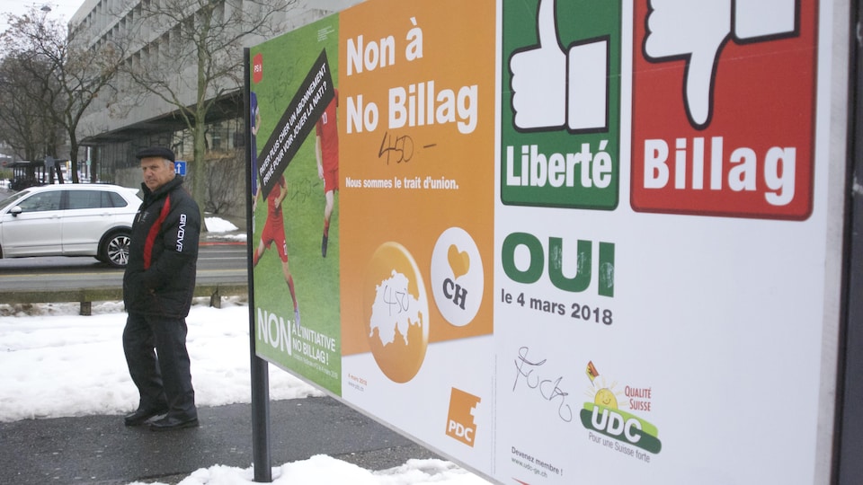 Un homme marche à côté d'une affiche sur le référendum en Suisse.