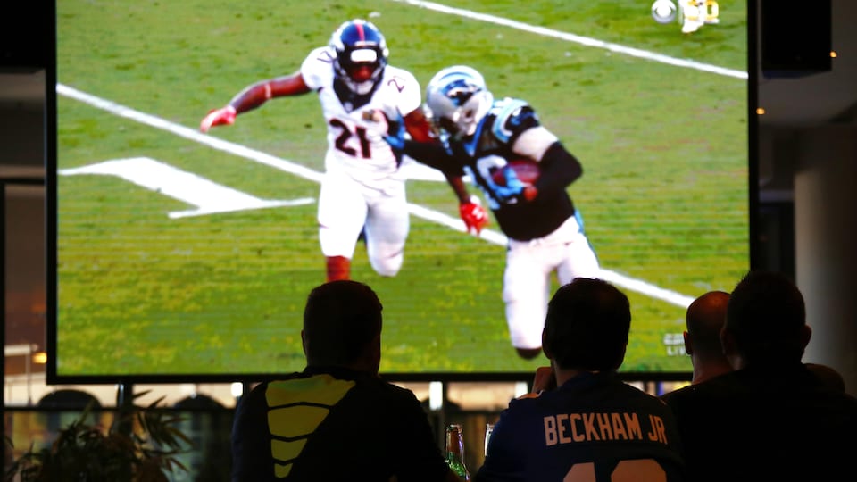 Des amateurs de football regardent le Super Bowl sur un écran géant.