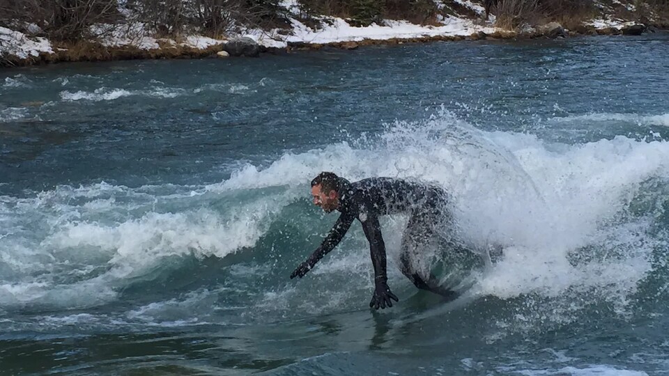 Un surfeur de rivière en train de surfer sur une vague.