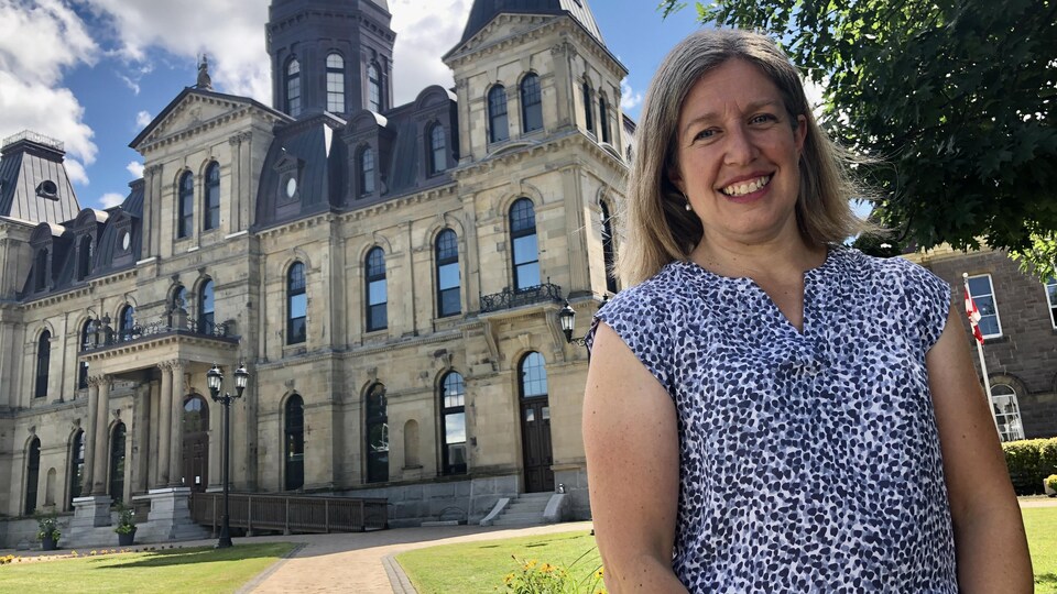 Une photo de Susan Holt, souriante, devant l'Assemblée législative du Nouveau-Brunswick. 