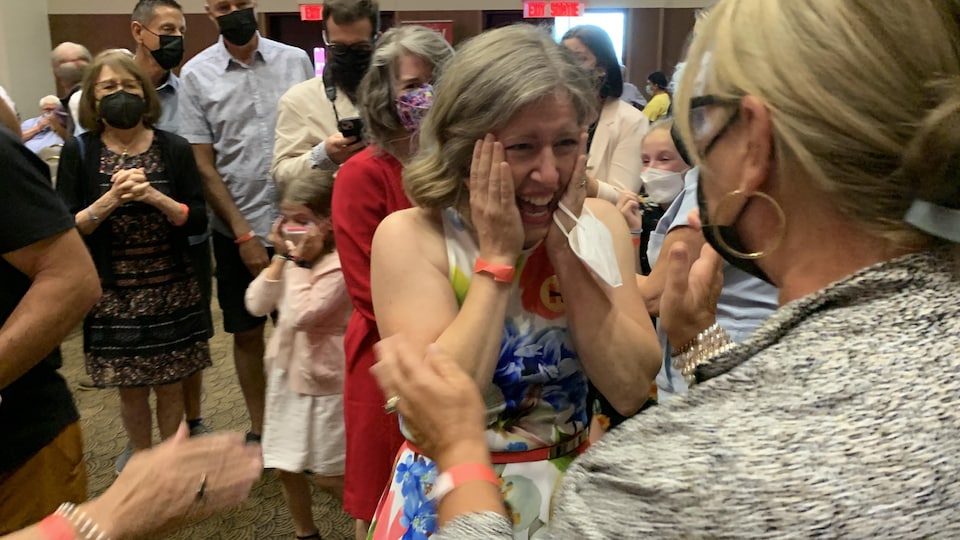 Entourée de gens qui appuyaient sa candidature, Susan Holt met ses deux mains sur ses joues et réagit avec joie à l'annonce de sa victoire.