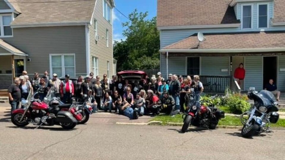 Une trentaine de motocyclistes devant une maison.
