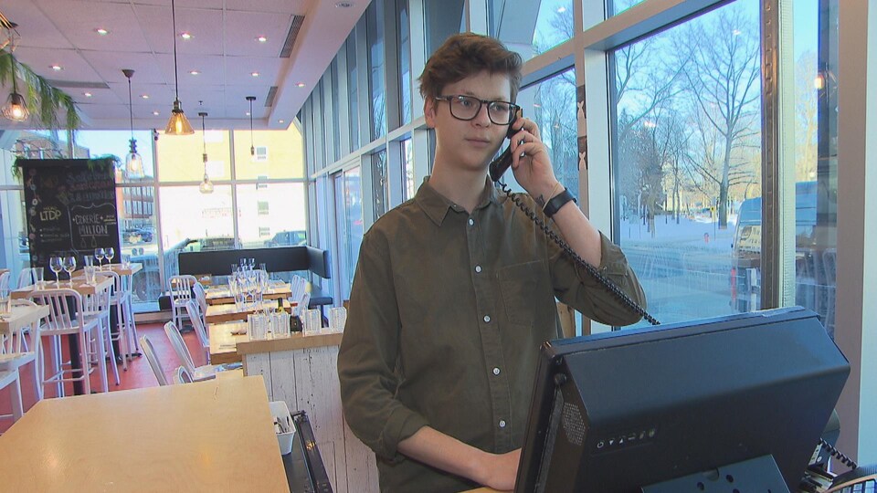 Un jeune homme répond au téléphone.