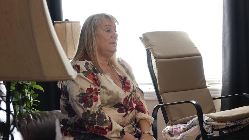 Une femme assise sur un sofa, vue de profil              