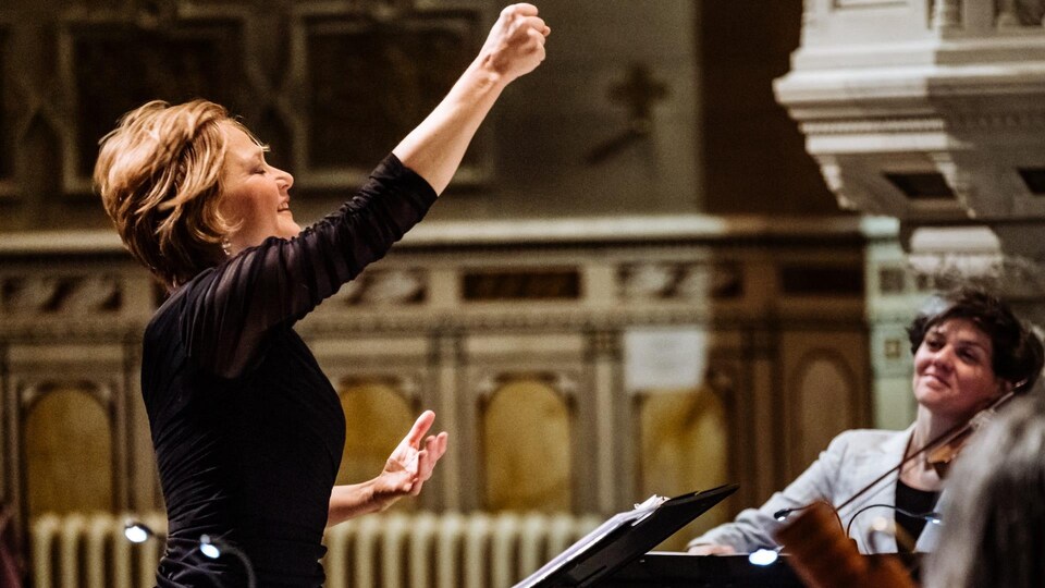 Suzie LeBlanc en train de diriger des musiciens, le point levé.