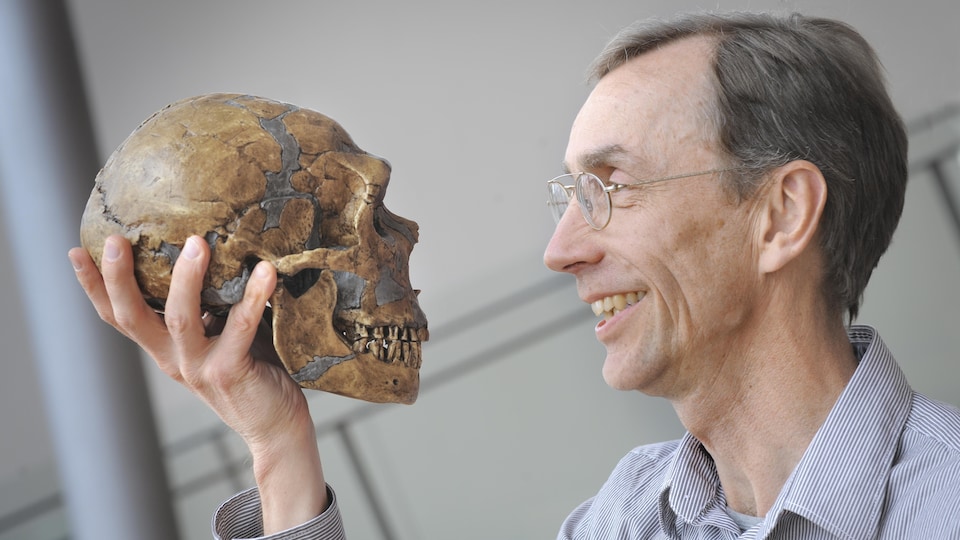 Svante Pääbo tient un crâne humain dans sa main.