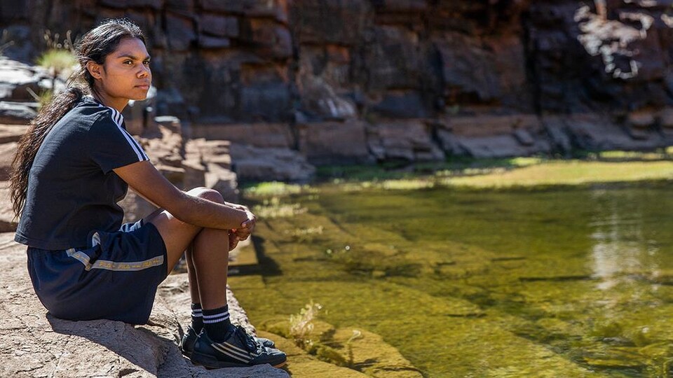 L'héroïne du film, une jeune adolescente, assise au bord d'un cours d'eau.
