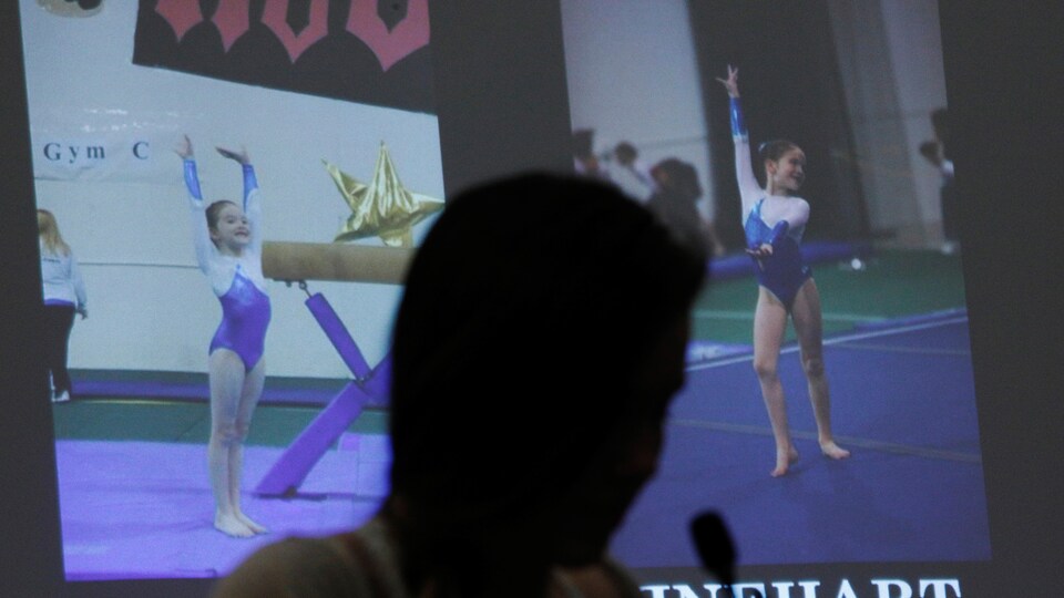 Jillian Swinehart, dans l'ombre d'une projection de photographies d'elle, petite fille, lorsqu'elle pratiquait la gymnastique, témoigne au procès de Larry Nassar.